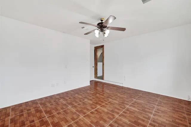 a view of a big room with wooden floor and chandelier fan