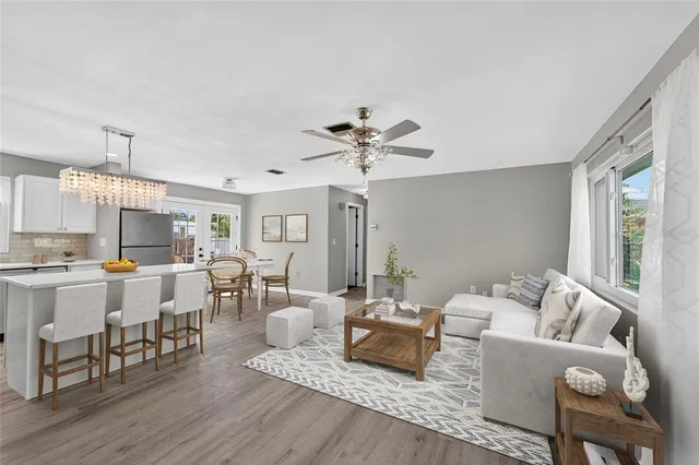 a living room with stainless steel appliances furniture a dining table and kitchen view