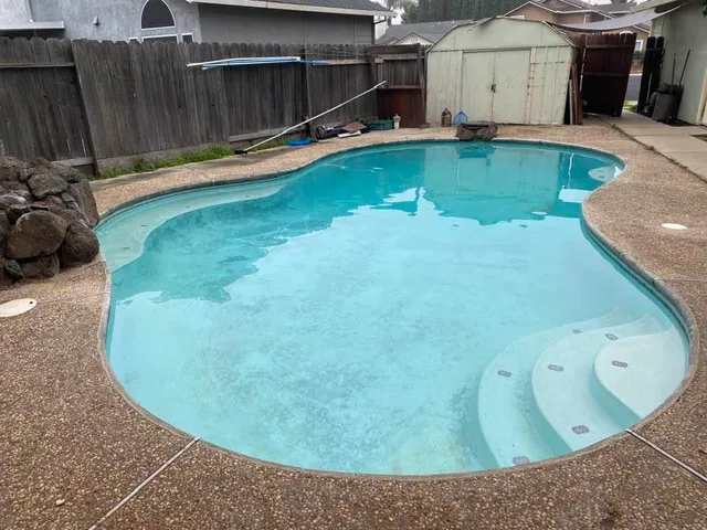 a view of a backyard with a tub and wooden fence
