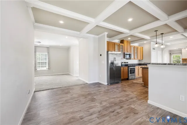 a kitchen with stainless steel appliances kitchen island granite countertop a refrigerator a stove and a sink with wooden floor