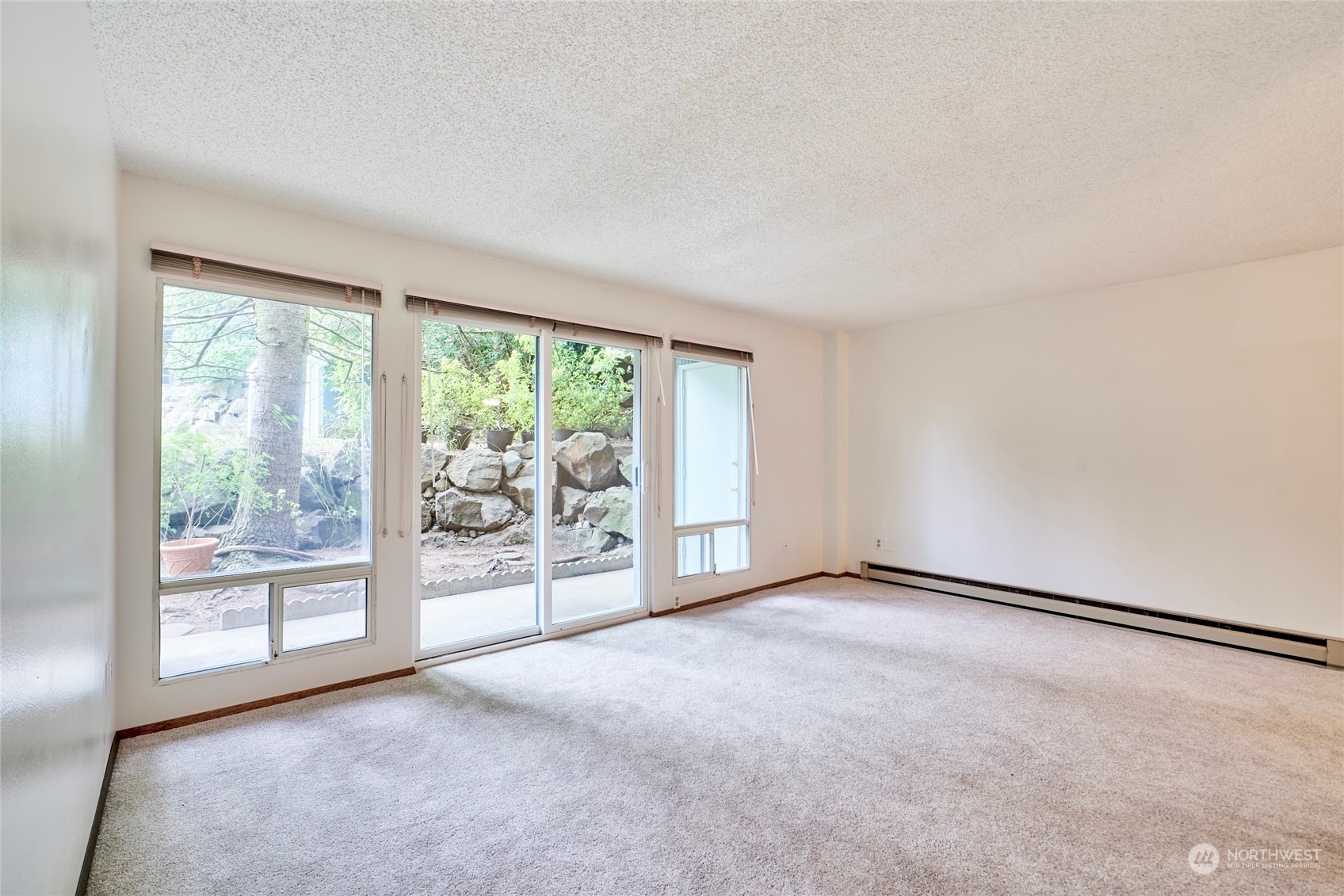 an empty room with floor to ceiling window and an outdoor view