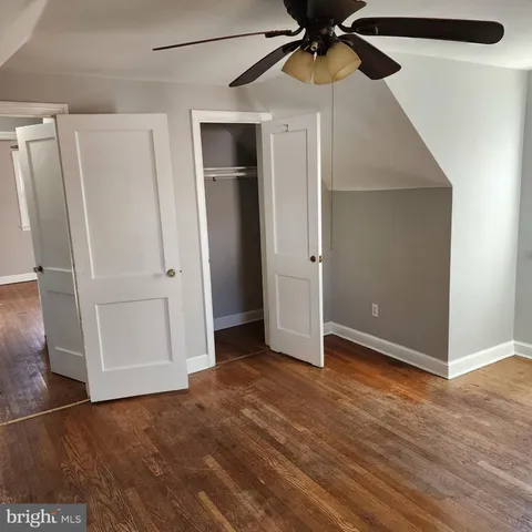 an empty room with wooden floor closet and windows
