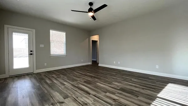 a view of empty room with wooden floor and fan