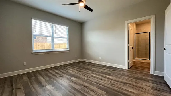 an empty room with wooden floor cabinet and windows