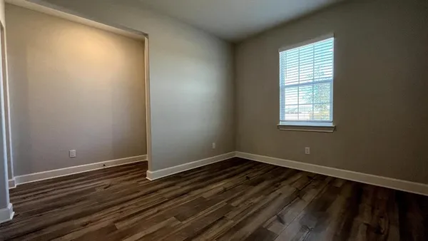 a view of an empty room with wooden floor and a window
