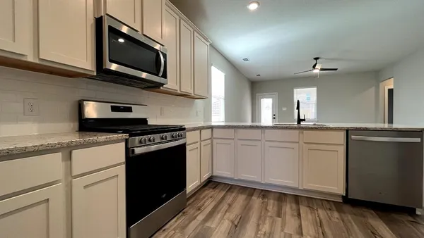 a kitchen with stainless steel appliances granite countertop a stove a sink and a microwave