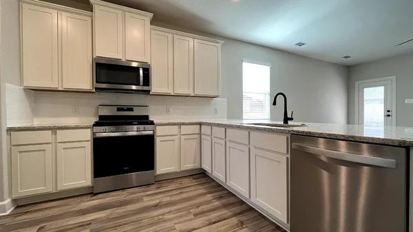 a kitchen with stainless steel appliances granite countertop a stove a sink and a microwave