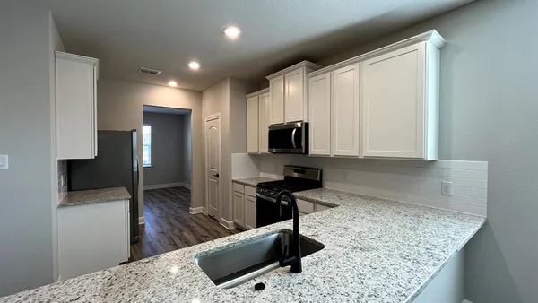 a kitchen with stainless steel appliances kitchen island granite countertop a sink refrigerator and microwave