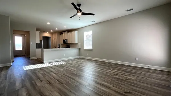 a view of a big room with wooden floor and a kitchen