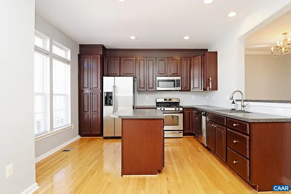 a kitchen with stainless steel appliances granite countertop a refrigerator a sink dishwasher a stove with wooden cabinets and floor