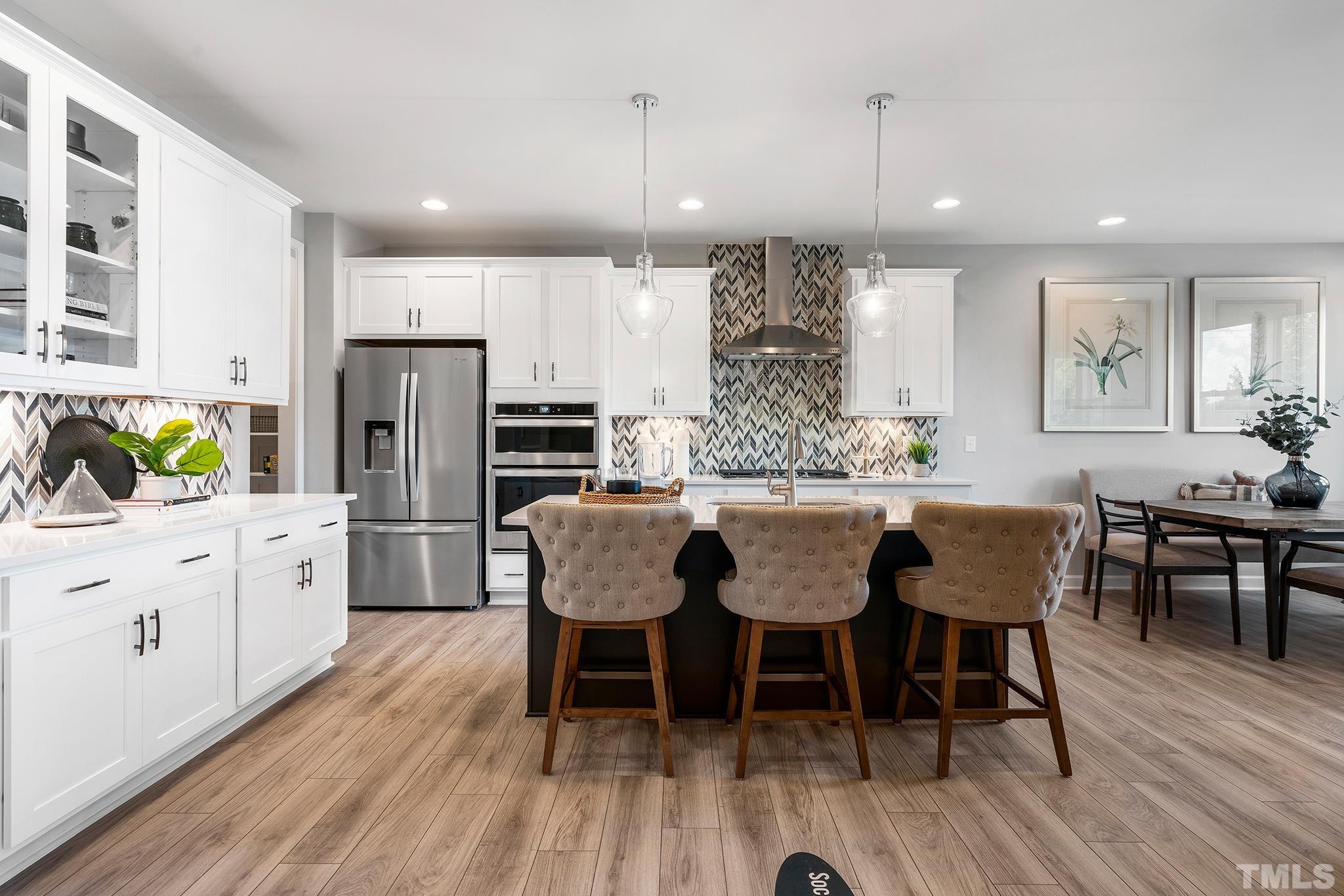 1016 Manchaca Loop, Unit 4 Apex, NC 27539 - Photo 11 of 36 a kitchen with stainless steel appliances granite countertop a dining table chairs refrigerator sink and cabinets