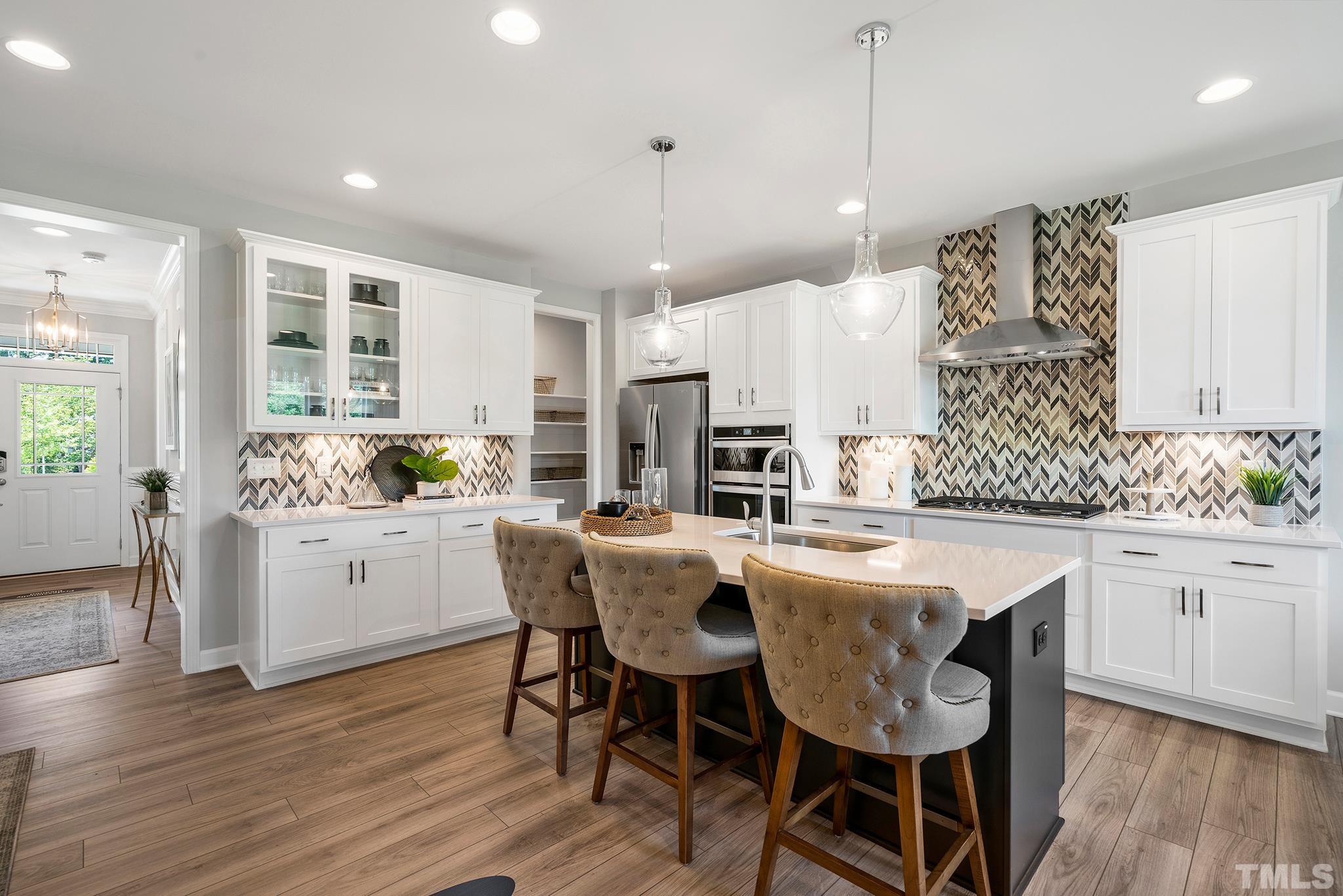 1016 Manchaca Loop, Unit 4 Apex, NC 27539 - Photo 5 of 36 a kitchen with stainless steel appliances kitchen island granite countertop a wooden floor and white cabinets