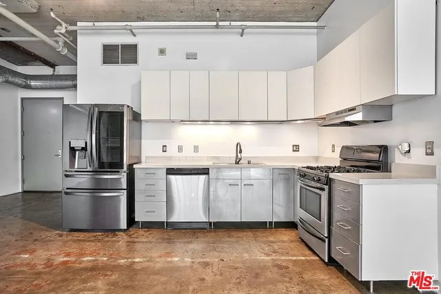 a kitchen with stainless steel appliances granite countertop a refrigerator a stove a sink and a microwave