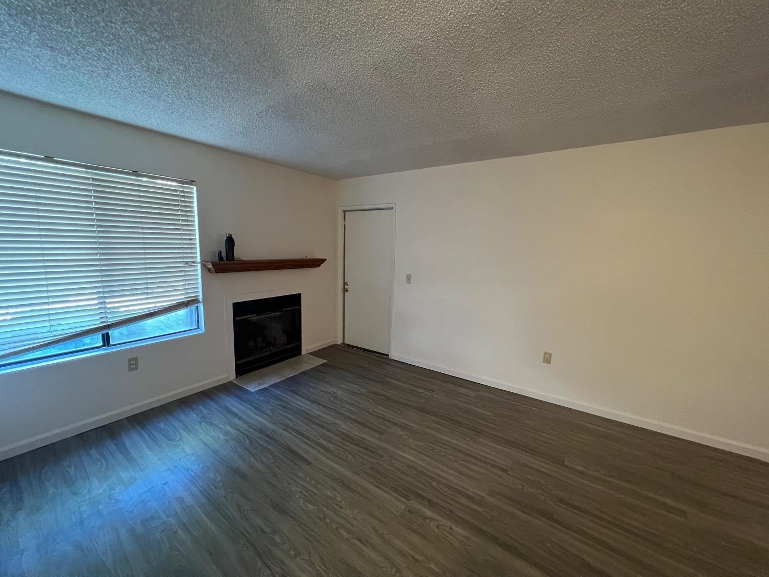 an empty room with wooden floor and fireplace