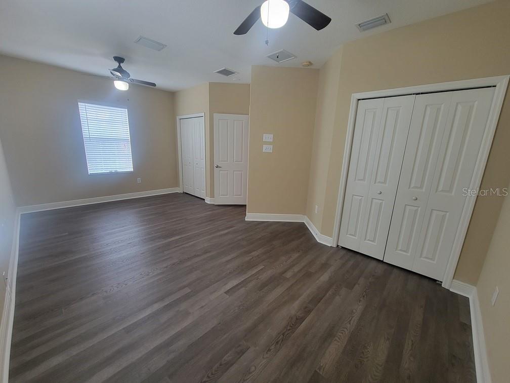 10418 Fenceline Road New Port Richey, FL 34655 - Photo 32 of 36 an empty room with wooden floor chandelier fan and windows