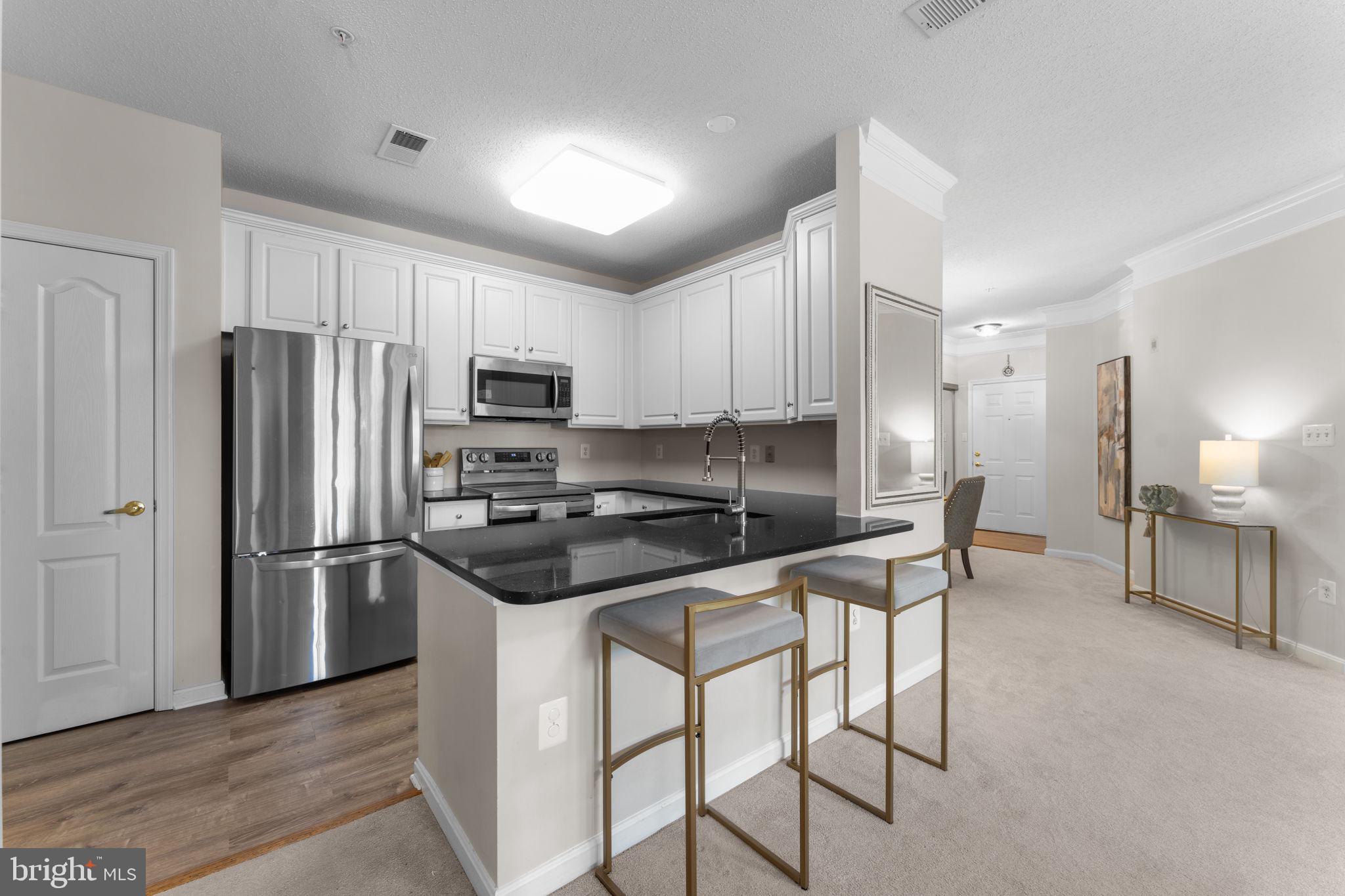12170 Abington Hall Place, Unit 201 Reston, VA 20190 - Photo 6 of 39 a kitchen with stainless steel appliances granite countertop a refrigerator stove microwave and sink