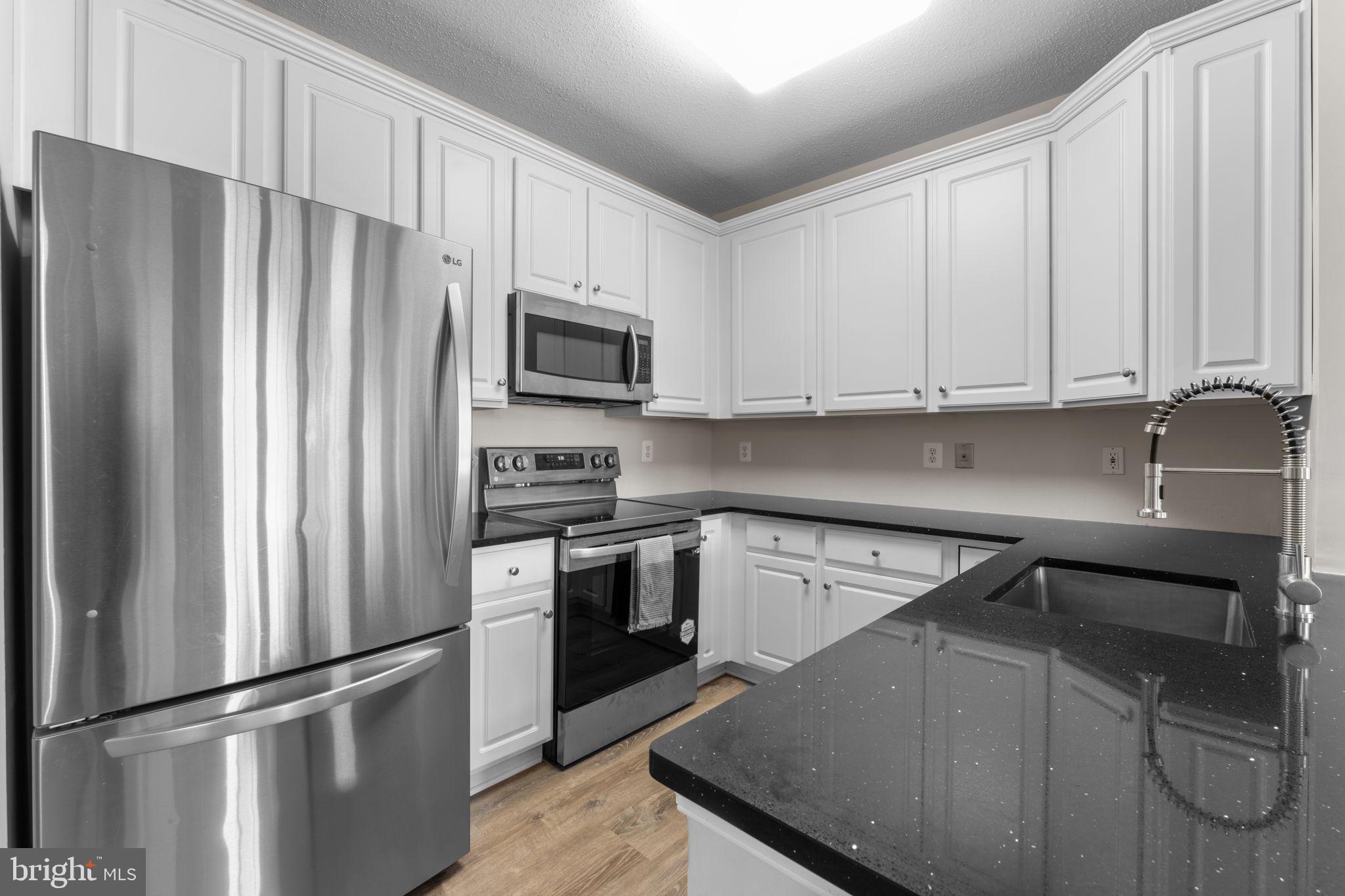 12170 Abington Hall Place, Unit 201 Reston, VA 20190 - Photo 7 of 39 a kitchen with granite countertop a refrigerator stove and microwave