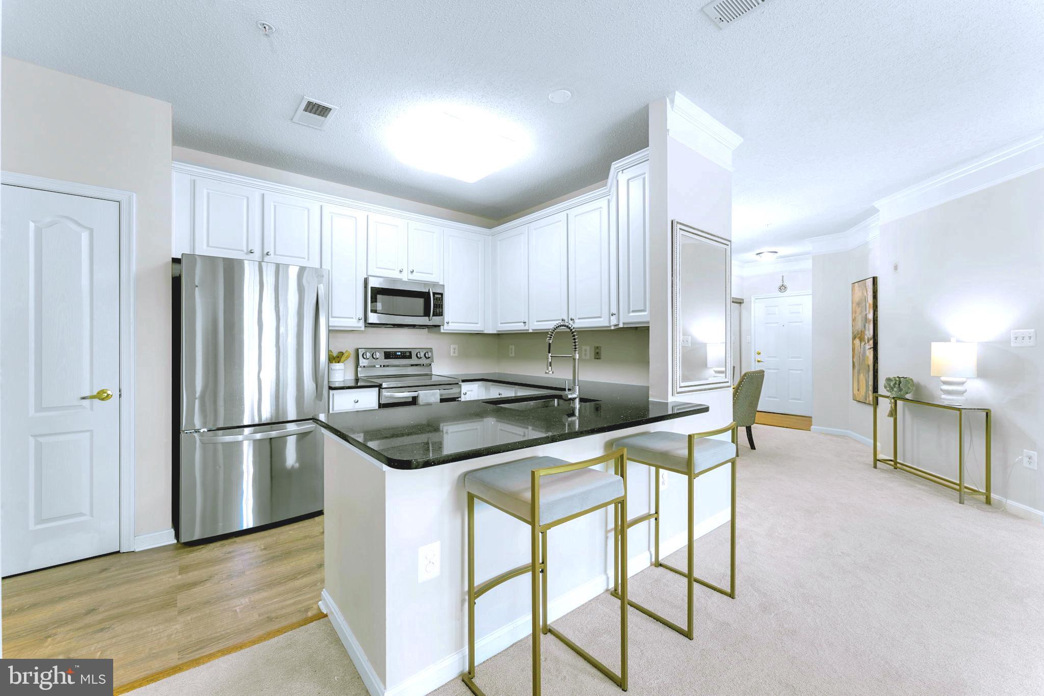 12170 Abington Hall Place, Unit 201 Reston, VA 20190 - Photo 9 of 39 a kitchen with stainless steel appliances granite countertop a refrigerator stove microwave and sink