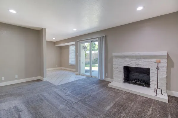 a view of an empty room with a fireplace and a window