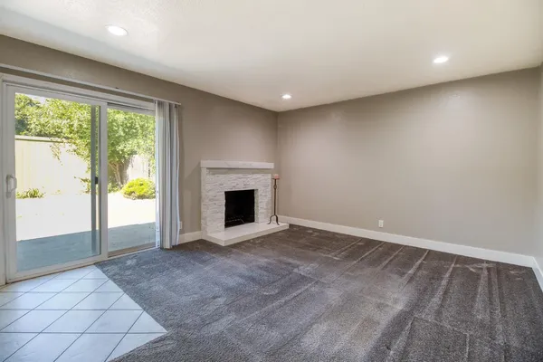 a view of an empty room with a fireplace and a window