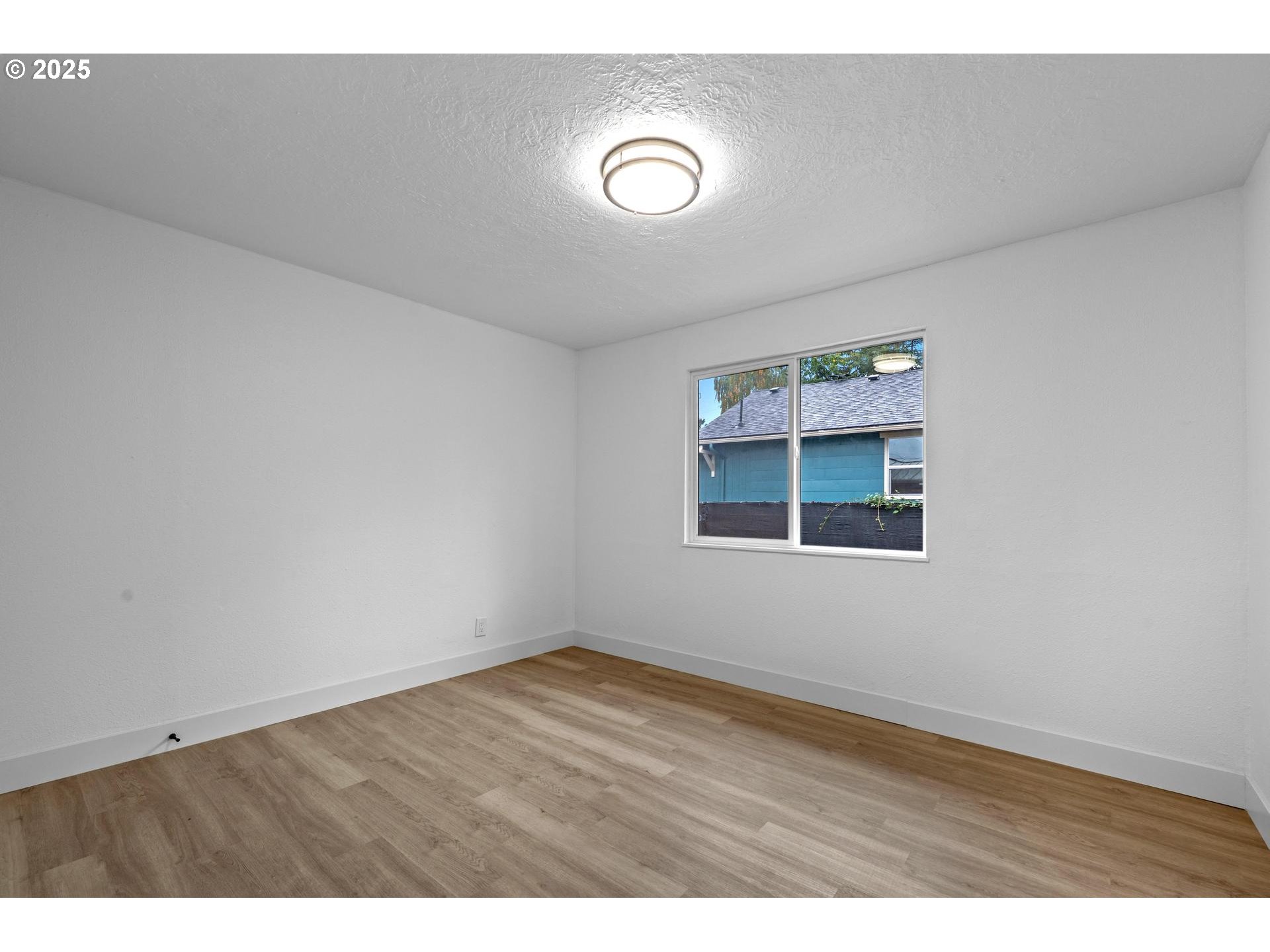 4804-4806 Northeast 111th Avenue Portland, OR 97220 - Photo 17 of 44 a view of an empty room with wooden floor and a window