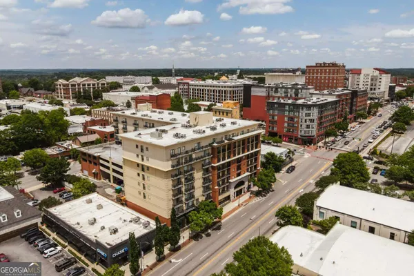 an aerial view of a multi story parking building with yard and mountain view in back