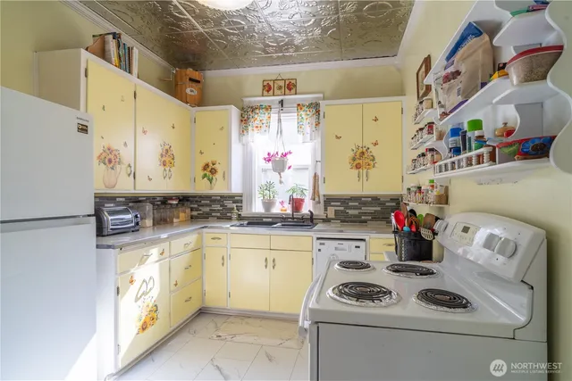 a kitchen with a sink dishwasher and white cabinets with wooden floor