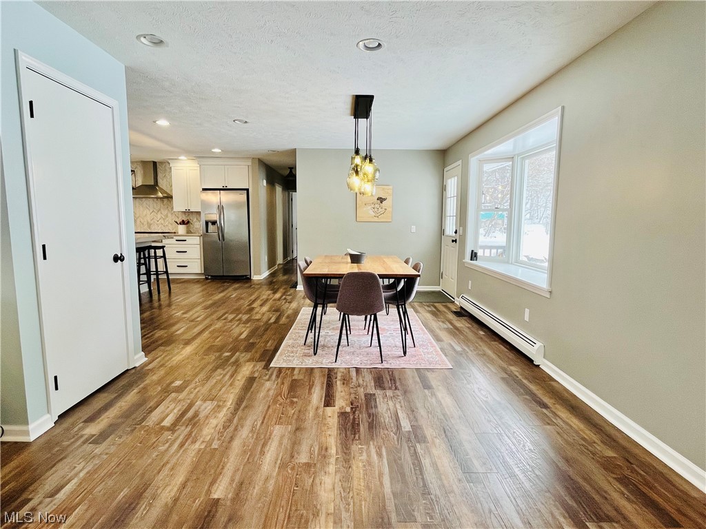 13655 Spring Street Burton, OH 44021 - Photo 4 of 48 Dining space with an inviting chandelier, baseboard heating, a textured ceiling, and wood-type flooring