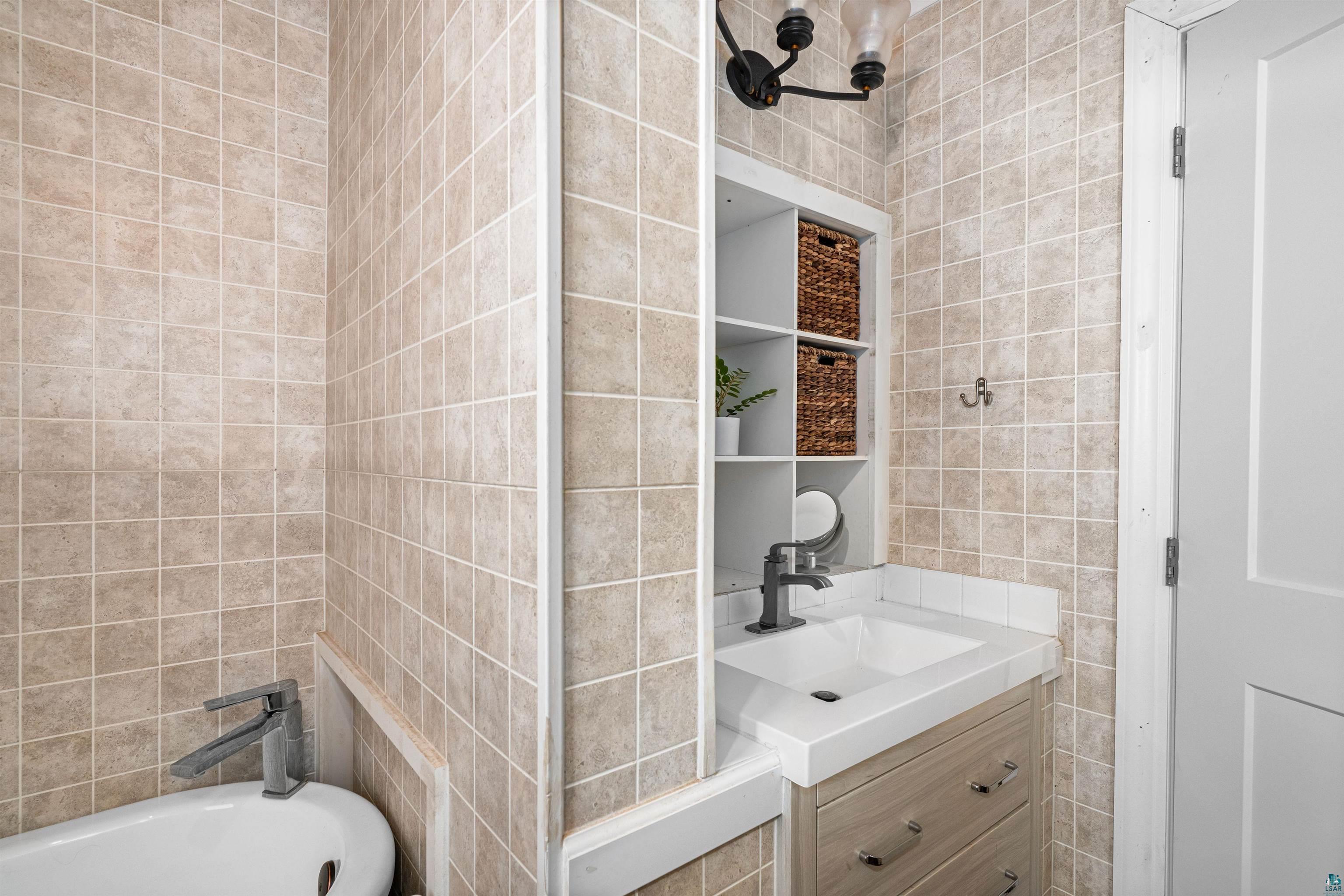 3325 Strand Road Duluth, MN 55803 - Photo 22 of 25 Bathroom vanity featuring an integrated sink with a matte black faucet, set within a light-toned wood-finish cabinet with drawer storage