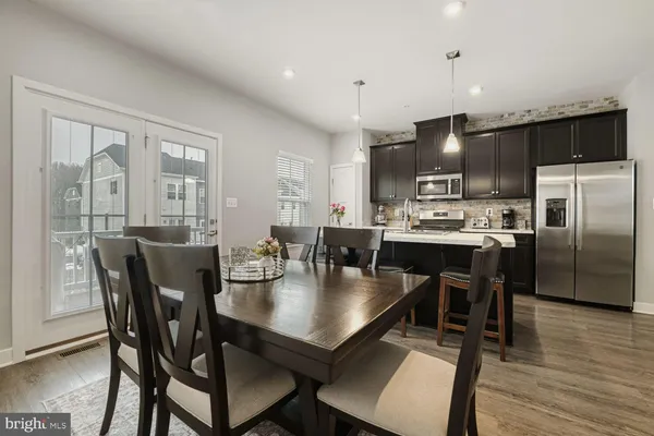 a kitchen with a dining table chairs and refrigerator