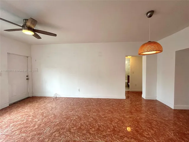 an empty room with a chandelier fan and windows