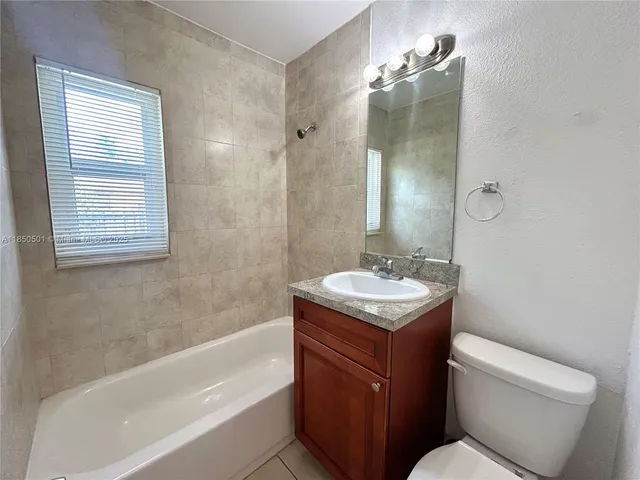 a bathroom with a granite countertop sink a toilet and bathtub