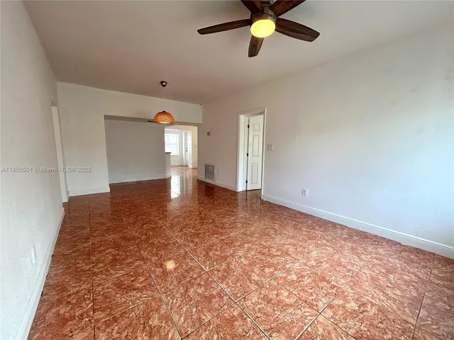 an empty room with a chandelier fan and windows