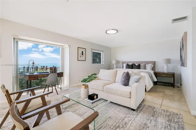 a bedroom with a bed a glass top table and a large window