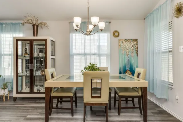a dining room with wooden floor a chandelier a wooden table and chairs