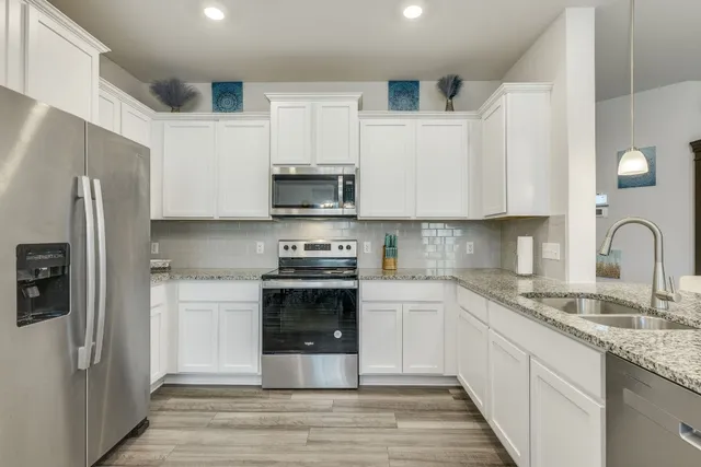 a kitchen with stainless steel appliances granite countertop a refrigerator sink and white cabinets