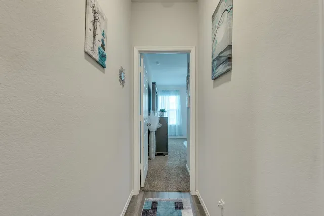 a view of a hallway with wooden floor and a bathroom