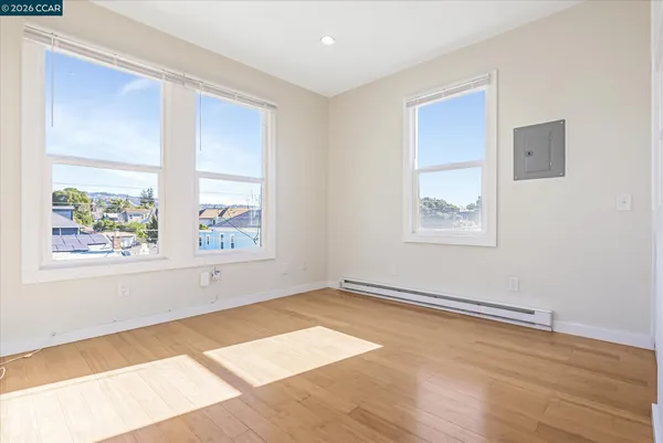 an empty room with wooden floor and windows