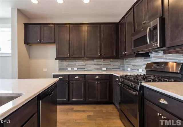 a kitchen with stainless steel appliances granite countertop a stove a sink dishwasher and a microwave oven on the stove