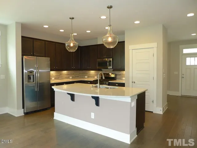 a kitchen with kitchen island stainless steel appliances a sink cabinets and wooden floor