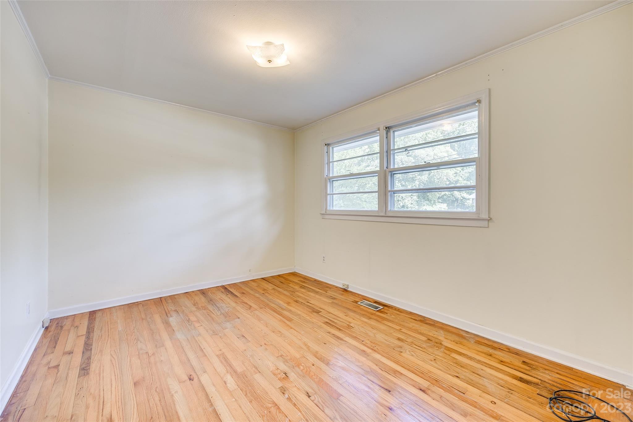 1136 East Woodlawn Road Charlotte, NC 28209 - Photo 7 of 27 an empty room with wooden floor and windows