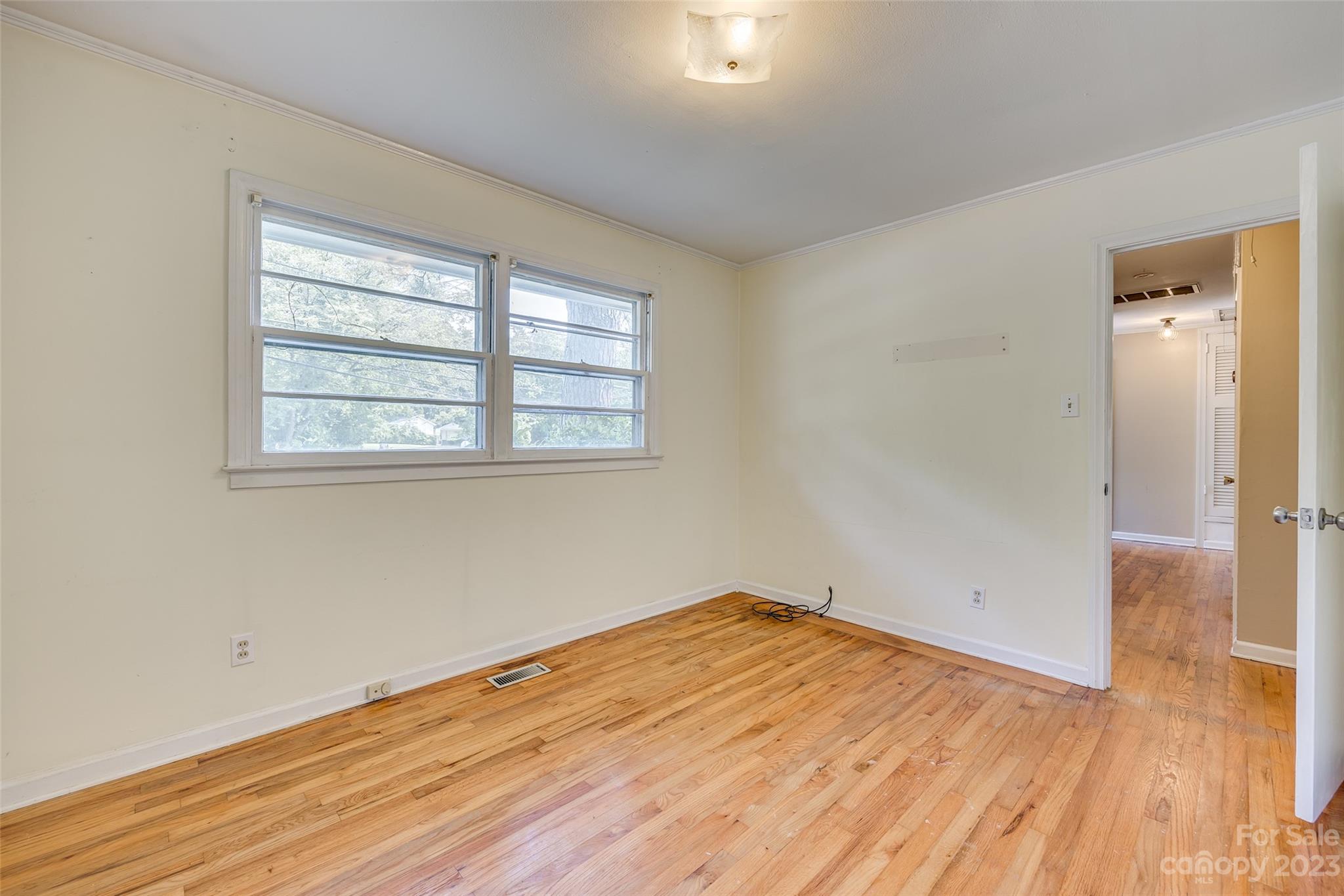 1136 East Woodlawn Road Charlotte, NC 28209 - Photo 8 of 27 an empty room with wooden floor and windows