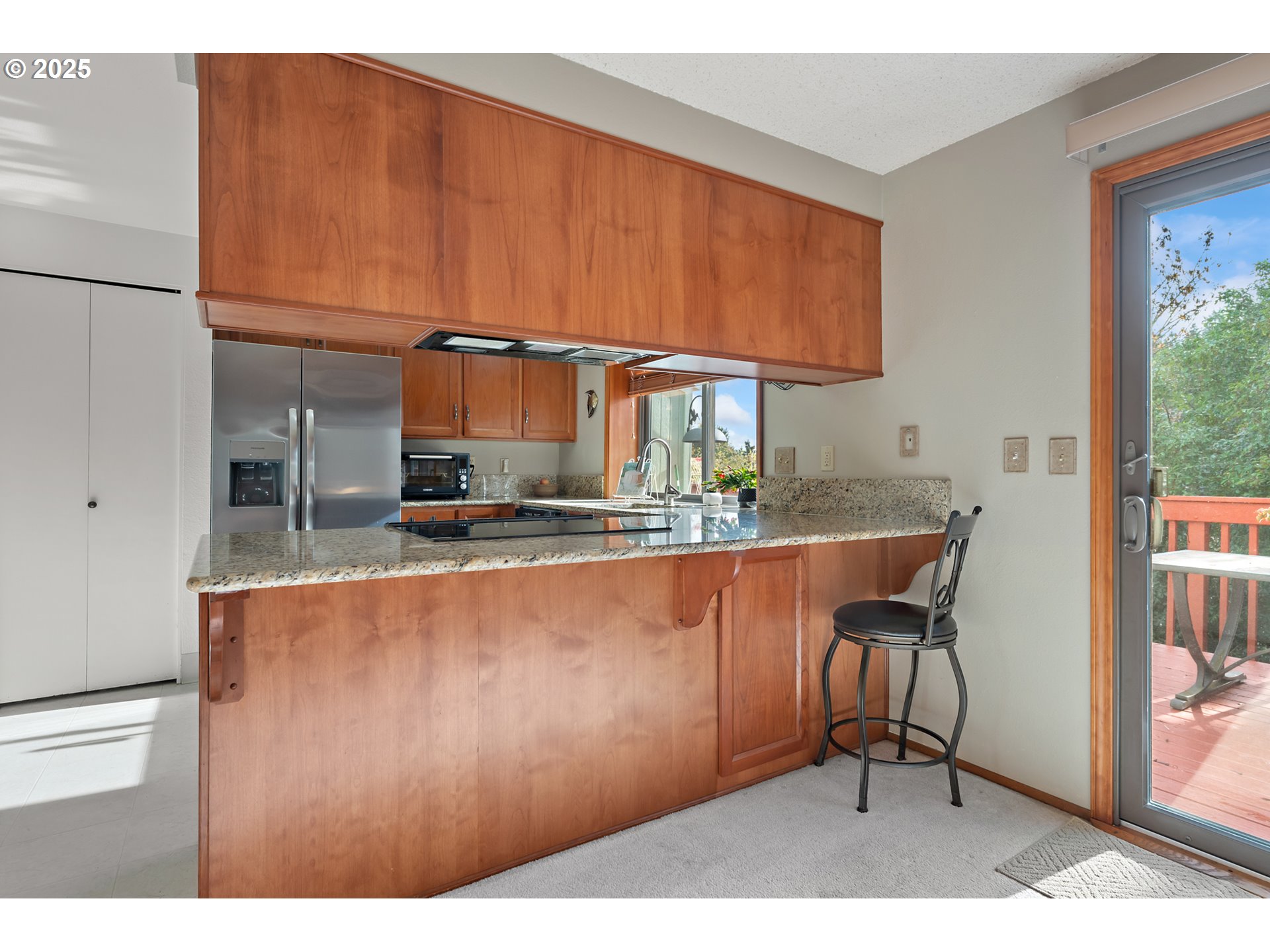 18100 Southwest Barcelona Way Beaverton, OR 97007 - Photo 11 of 41 a kitchen with stainless steel appliances kitchen island granite countertop a table chairs and a wooden cabinets
