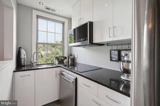 a kitchen with stainless steel appliances granite countertop a sink and a stove next to a window