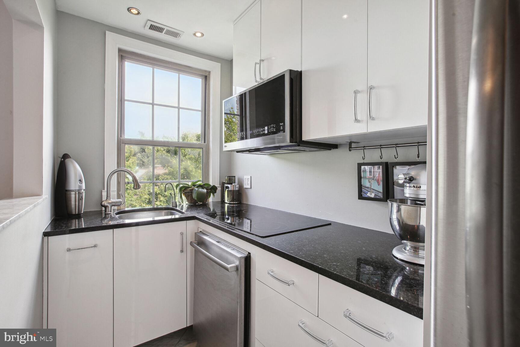 18 9th Street Northeast, Unit 401 Washington, DC 20002 - Photo 10 of 16 a kitchen with stainless steel appliances granite countertop a sink and a stove next to a window