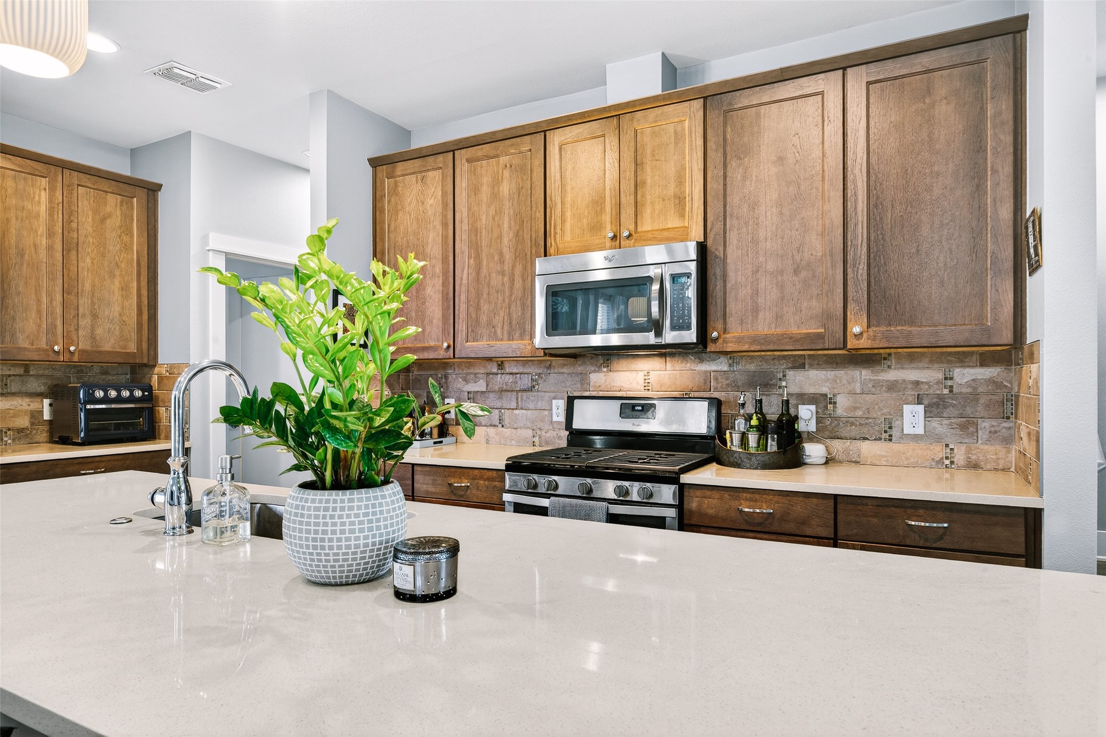 4917 Sunset Trail, Unit A Austin, TX 78745 - Photo 8 of 36 Kitchen with stainless steel appliances, decorative backsplash, wood finish cabinets, and light stone countertops