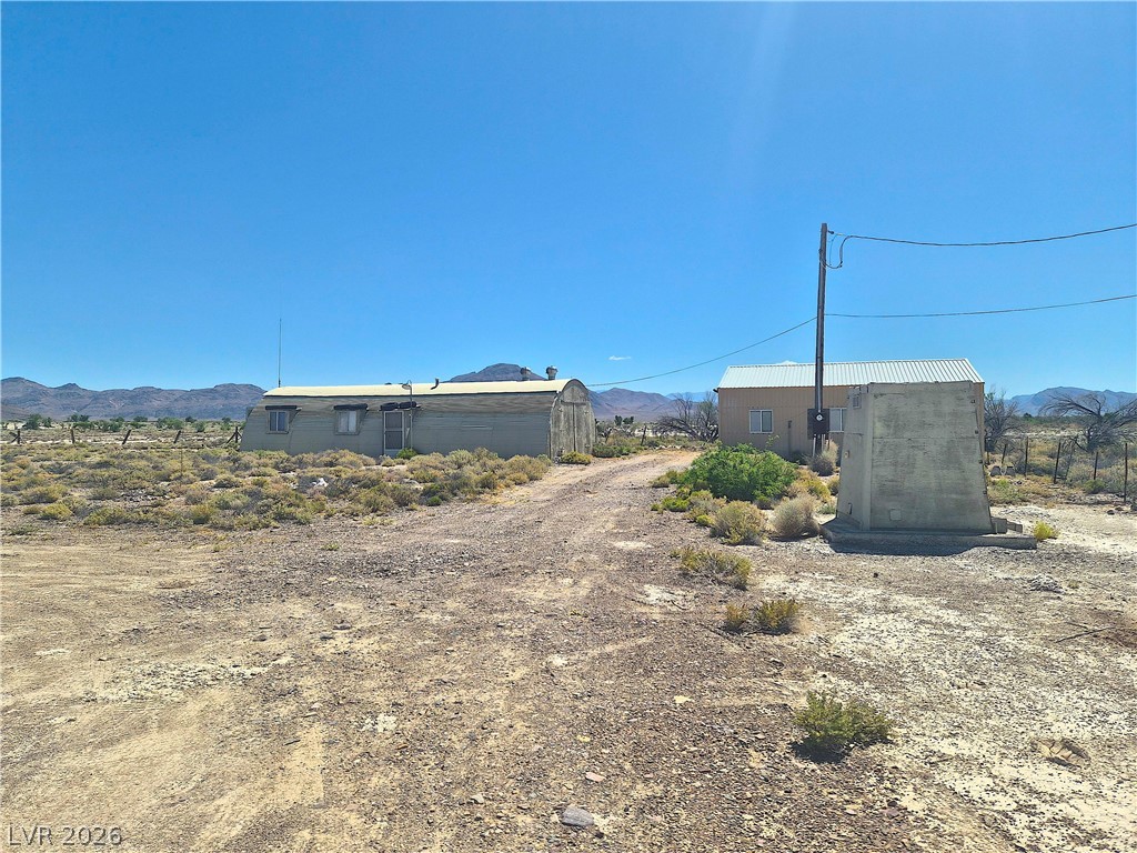 11545 South Spring Meadows Road Pahrump, NV 89060 - Photo 4 of 33 This property features two distinct structures nestled in a vast, open landscape with mountain views.