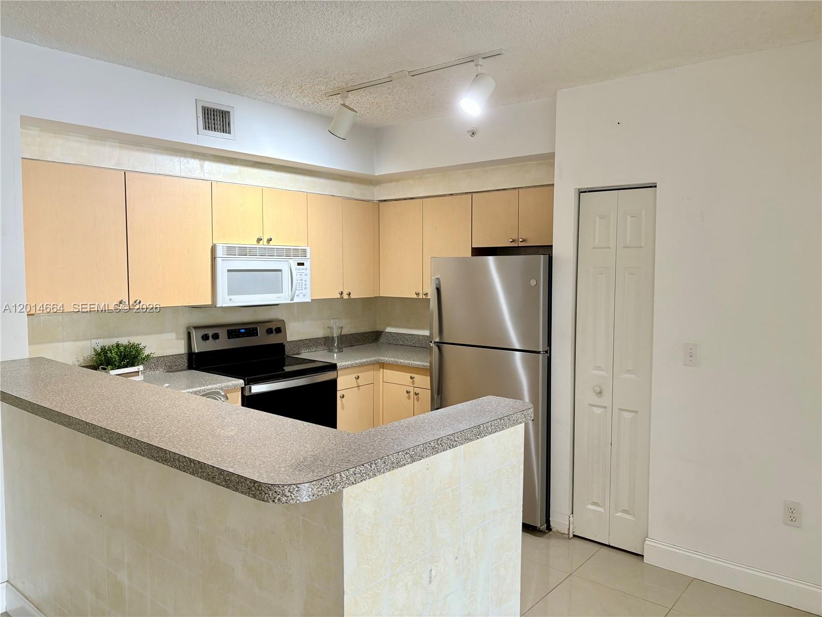 8030 North Nob Hill Road, Unit 105 Tamarac, FL 33321 - Photo 6 of 22 a kitchen with stainless steel appliances a refrigerator sink and white cabinets