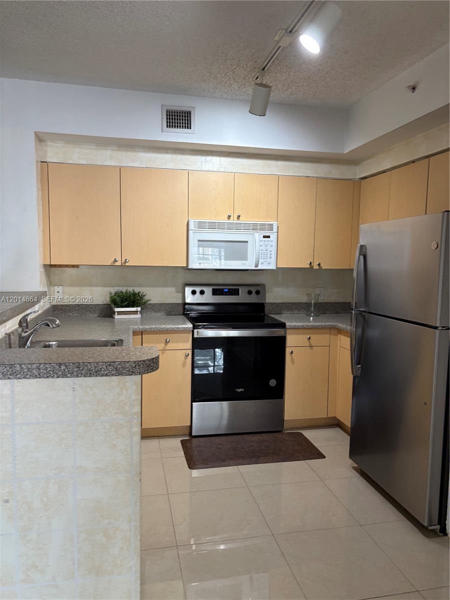 8030 North Nob Hill Road, Unit 105 Tamarac, FL 33321 - Photo 8 of 22 a kitchen with a stove a sink and a refrigerator