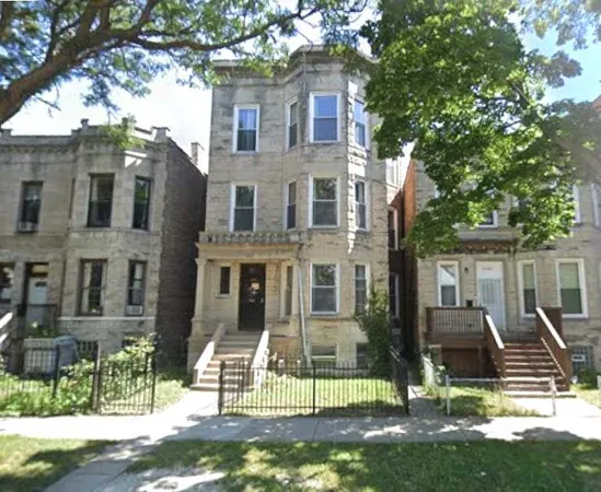 a view of a brick house with many windows and a big yard